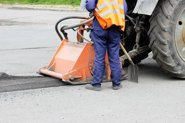 Hortumlu bir traktör yolu onarıyor. Çukurlara yama onarımı.