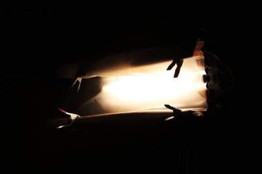 Tripodun üzerinde floresan lambalar ve çamaşır iğneleriyle sabitlenmiş ince bir filtre olan bir aydınlatma cihazı film çekimi sırasında evin içini aydınlatmak için kullanılır..