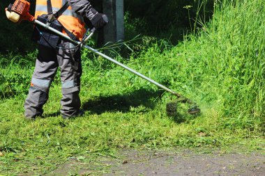 Bir budama makinesi ile çim biçen bir işçi