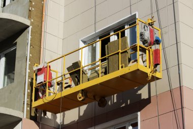 Sarı asma beşik işçi bir yeni inşa edilen yüksek katlı bina yalıtımı için çevre kurulları bağlar