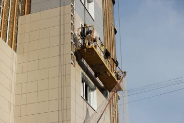 Sarı asma beşik işçi bir yeni inşa edilen yüksek katlı bina yalıtımı için çevre kurulları bağlar