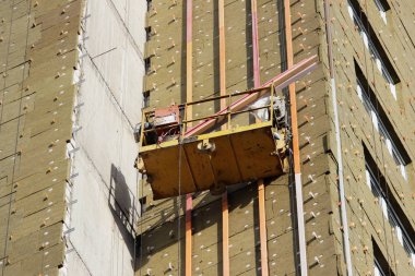 Sarı asma beşik işçi bir yeni inşa edilen yüksek katlı bina yalıtımı için çevre kurulları bağlar