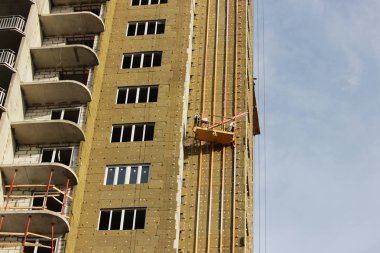 Sarı asma beşik işçi bir yeni inşa edilen yüksek katlı bina yalıtımı için çevre kurulları bağlar
