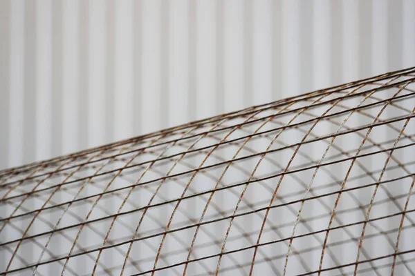 The bent sheet of metal iron reinforcement against the background of beige siding.