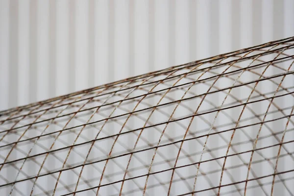 The bent sheet of metal iron reinforcement against the background of beige siding.