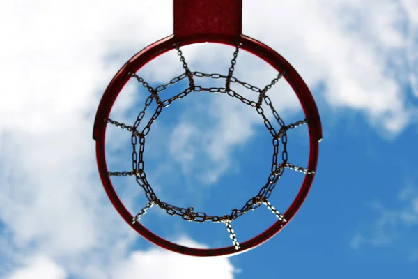 Basquete vermelho vista aro de baixo contra o céu azul — Fotografia de Stock