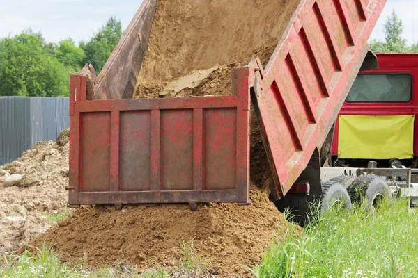 Stavební náklaďák uvolní písku na místě opravit, kde položení potrubí s vodou. Žlutá prázdné reklamní markýzy na kabiny — Stock fotografie
