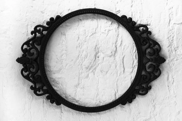 An oval patterned empty metal frame on a white wall background. black and white photo — Stock Photo, Image