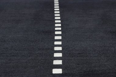 Siyah asfalt üzerinde yeni beyaz aralıklı yol işaretleri