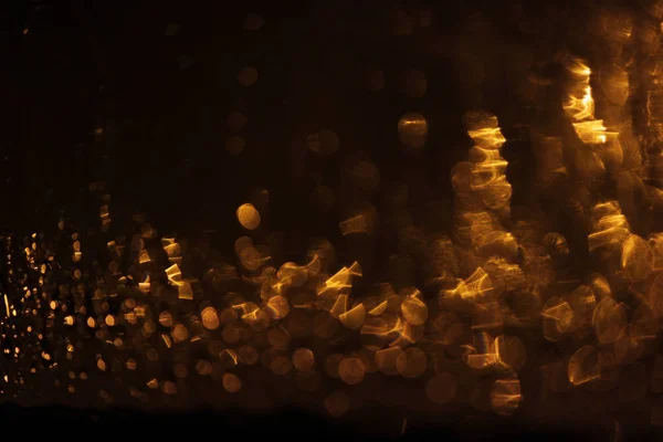 Altın renkli bir bardağa gece yağmuru damlaları, fenerlerin ışığı. Bokeh