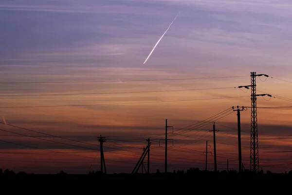 日没のパイロン高電圧電源ライン 日没の背景に電線を持つ金属構造物の大塔 — ストック写真