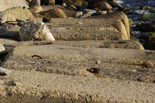 Kıyıyı erozyondan korumak için büyük beton dikdörtgen bloklar denizde yatıyor. Demiryolu raylarının kapatılması.