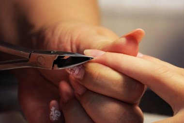 Eğitim kursları, manikürcü öğrenciler nasıl çivi kerpeten cuticles yardımıyla gomalak uygulamadan önce işleneceğini gösterir.