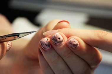 Manikür kursunda okuyan bir öğrenci, bir bayan müşterinin elini manikür makası ile manikür makası ile hazırlar..