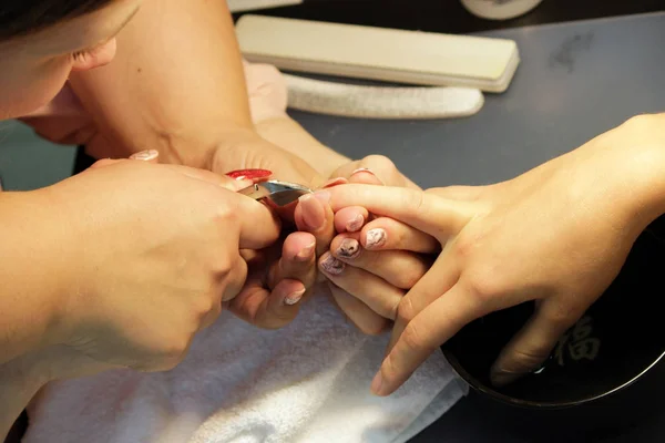 manicurist at training courses shows students how to handle nails with the help of nippers cuticles before applying shellac