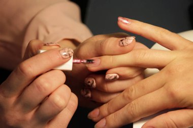 Manikür kursunda okuyan bir öğrenci renk jeli kabuğu uyguluyor. pembe altın rengi.