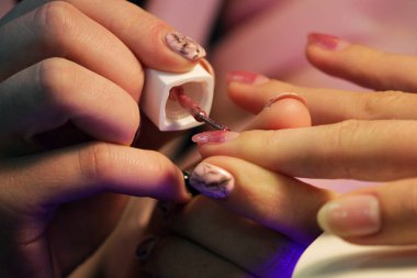 Manikür kursunda okuyan bir öğrenci renk jeli kabuğu uyguluyor. pembe altın rengi.