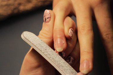 Bir öğrenci bir manikür eğitim kursları, Bayan istemci el bir dosya ile gomalak uygulamadan önce hazırlar