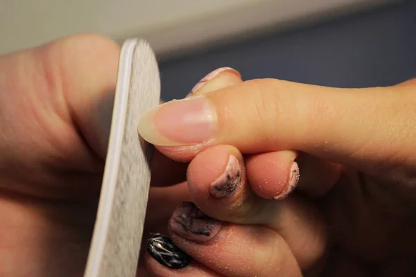 A student at the training courses of a manicure prepares the hand of a lady client with a file before applying shellac