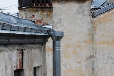 Galvanize çarşaflar ve yağmur suyu borularıyla kaplı eski tuğla evlerin çatıları. Saint-Petersburg, Rusya.