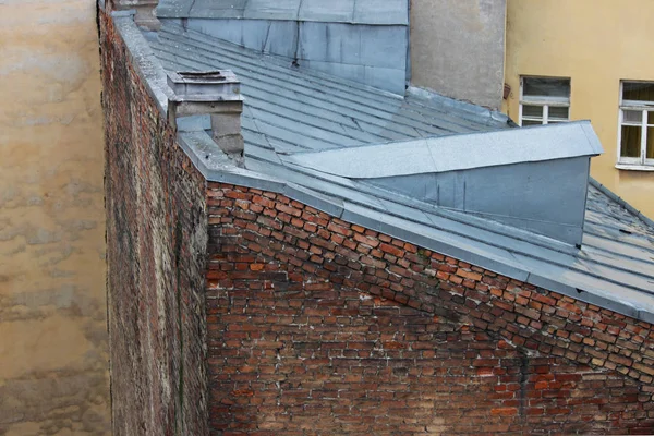 Galvanizli çarşaflarla kaplı eski tuğla evlerin çatıları. Saint-Petersburg, Rusya.