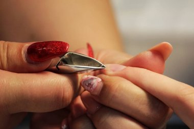 Eğitim kursları, manikürcü öğrenciler nasıl çivi kerpeten cuticles yardımıyla gomalak uygulamadan önce işleneceğini gösterir.