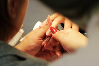 Eğitim kursları, manikürcü öğrenciler nasıl çivi kerpeten cuticles yardımıyla gomalak uygulamadan önce işleneceğini gösterir.