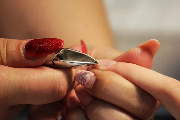 manicurist at training courses shows students how to handle nails with the help of nippers cuticles before applying shellac