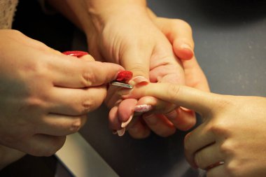 Eğitim kursları, manikürcü öğrenciler nasıl çivi kerpeten cuticles yardımıyla gomalak uygulamadan önce işleneceğini gösterir.