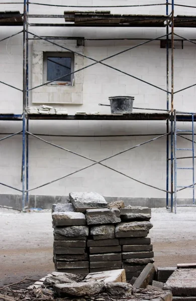 Oprava práce - lešení, kbelík s cementem, okno. světlá omítka na stěně a chodníkových. — Stock fotografie