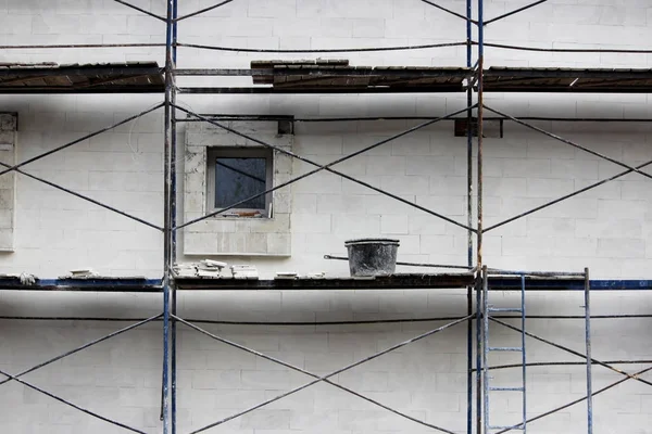 Reparaturarbeiten - Gerüst, Eimer mit Zement, Fenster. heller Putz an der Wand. — Stockfoto