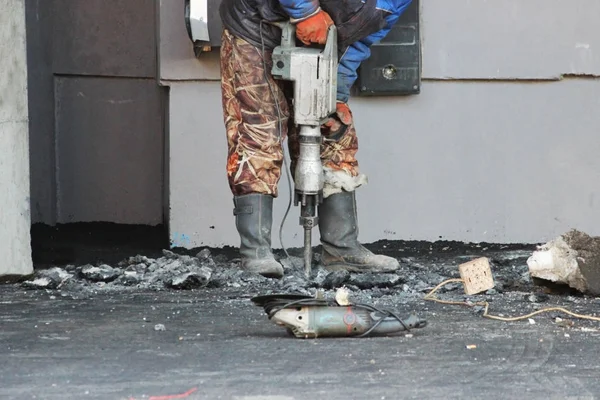 Road repairing works with jackhammer. Male worker using jackhammer pneumatic drill machinery on road repair. Arkhangelsk. — Stock Photo, Image