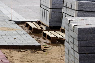 İnşaat için birçok kaldırım taşları inşaat alanındaki paletler üzerine döşenmiş levhalar şehir meydanında çalışır.