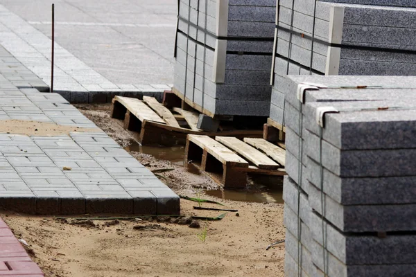 İnşaat için birçok kaldırım taşları inşaat alanındaki paletler üzerine döşenmiş levhalar şehir meydanında çalışır.