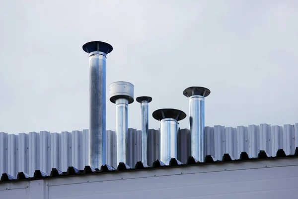 Cinco tubos de chimenea de acero inoxidable en el techo de la casa . — Foto de Stock