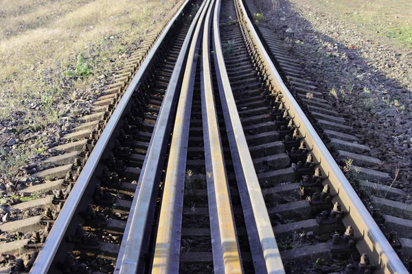 Πολλούς σιδηροτροχιών βρίσκονται στους στρωτήρες μεταξύ των κύριο σιδηροτροχιών επί της σιδηροδρομικής γραμμής. βίδες που συγκρατούν τις σιδηροτροχιές στρωτήρες για την κατεύθυνση των σιδηροδρομικών — Φωτογραφία Αρχείου