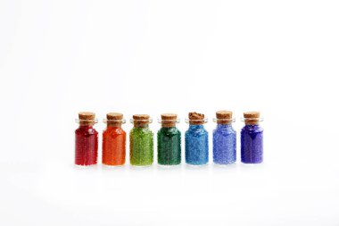 Boncuklar, beyaz bir arka plan üzerinde bir gökkuşağı renkleri ile dolu bir mantar tıpa, yedi küçük cam şişe