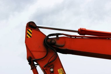 Tren turuncu bir yükleyici aygıt. Gökyüzüne karşı hidrolik sistemi.