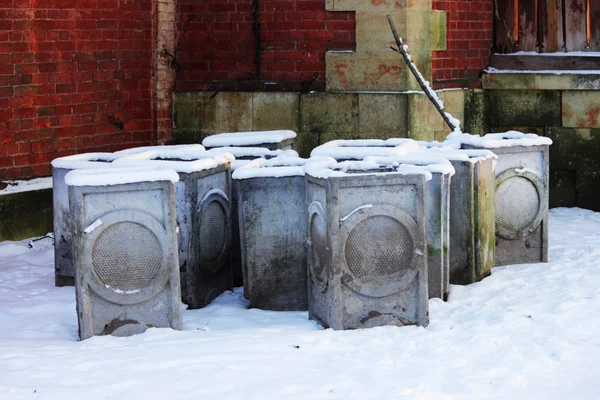 Ein paar betongraue Müllurnen stehen in einem Park im Schnee. — Stockfoto