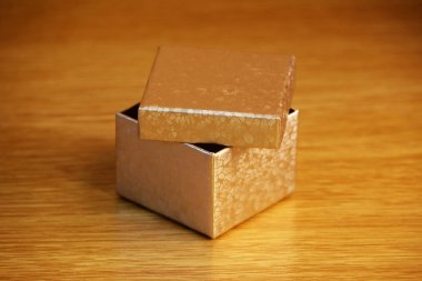 Işık sarı ahşap arka plan üzerinde küçük bir altın kutu. yumuşak yansıtıcı ışık