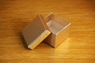 Işık sarı ahşap arka plan üzerinde küçük bir kare altın kutu. yumuşak yansıtıcı ışık