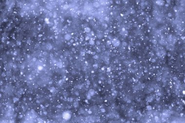 Kışın güneş ışığı önünde gökten kar düşüyor.