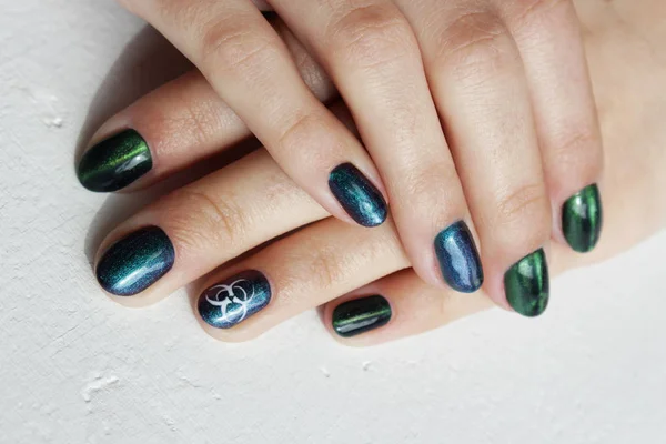 hands of a young girl with green manicure, which shows a sign of biological danger biohazard.