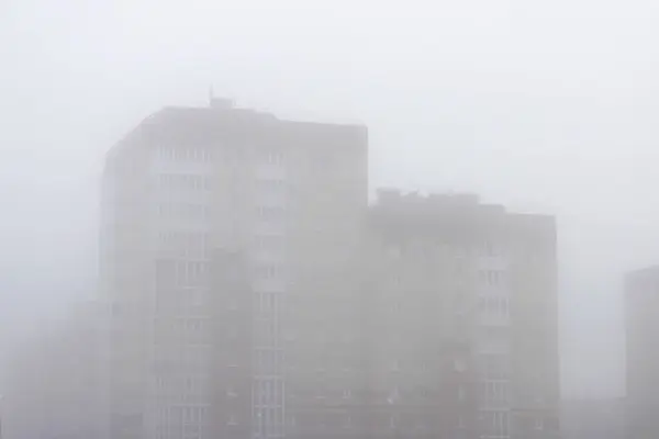 Une maison de ville à plusieurs étages dans un brouillard tôt le matin au printemps . — Photo