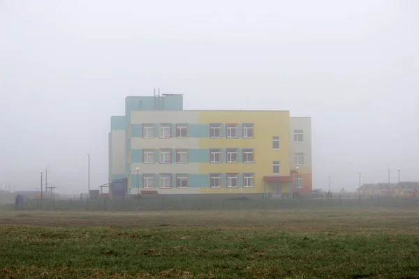 A lonely coloful house in the fog in a vacant lot in the spring early in the morning. — Stock Photo, Image