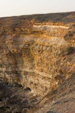 Mavi deniz ve kayalık uçurum batan güneş tarafından aydınlatılıyor. dikey resim.