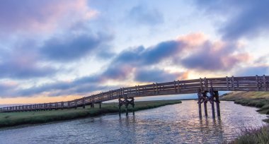 Don Edwards San Francisco Bay Ulusal Yaban hayatı sığınağında yaya köprüsü geçiş tuz buharlaşma gölet günbatımı manzarası. Fremont, Alameda County, Kaliforniya, ABD.