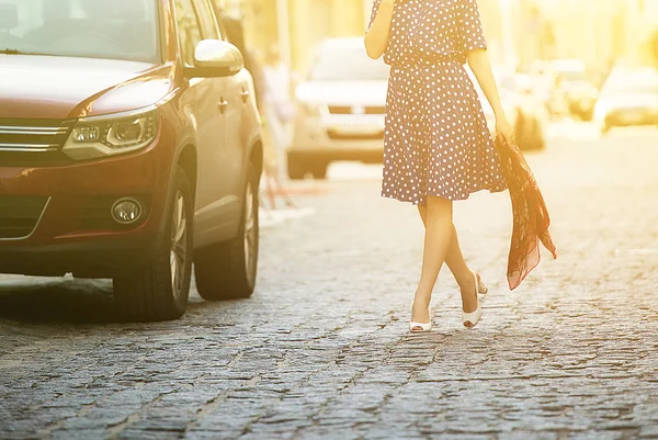 Jovem bela mulher em um vestido azul descendo a rua ao lado do carro, segurando uma camisola em suas mãos — Fotografia de Stock