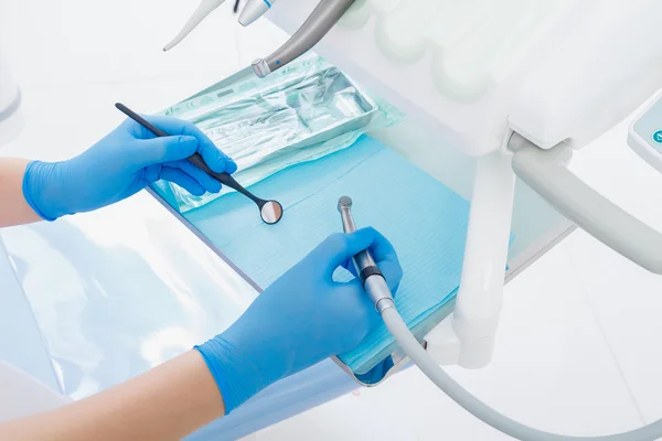 Closeup hands of dentist holding tools and a mirror in the dental office — Stock Photo, Image