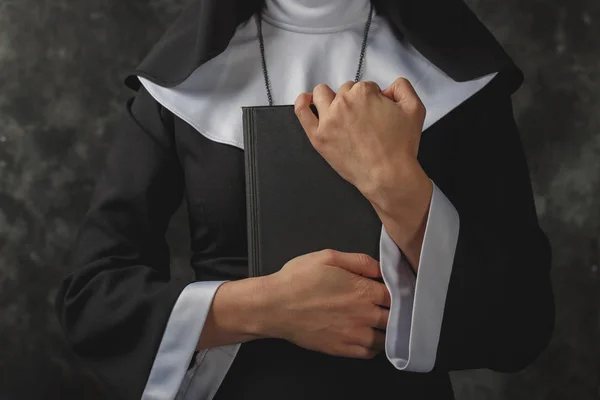 Primer plano de las manos de las monjas que presiona contra su pecho Biblia.Religiosa monja en el concepto de religión fondo oscuro — Foto de Stock